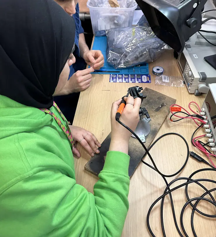 Maryam soldering a badge for Onside's makers room