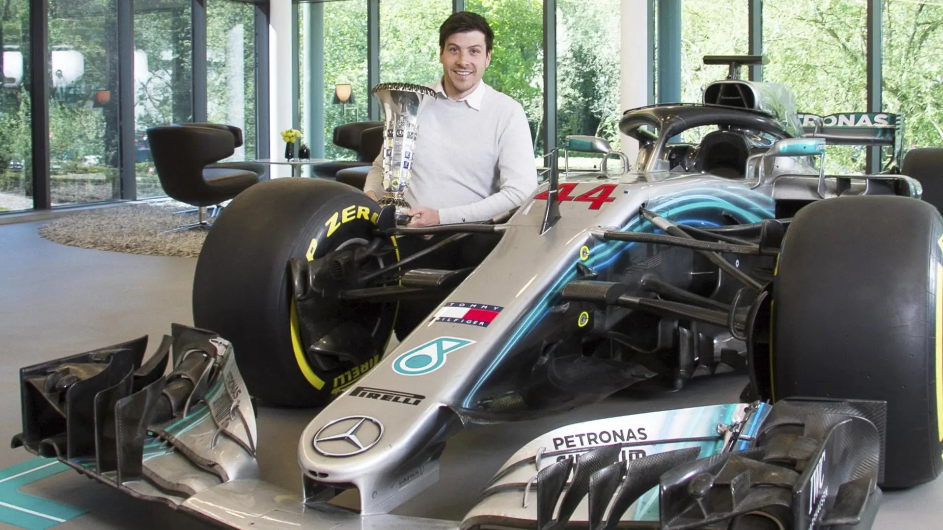 Alumni Austin O'Brien crouched next to a Mercedes Formula 1 car