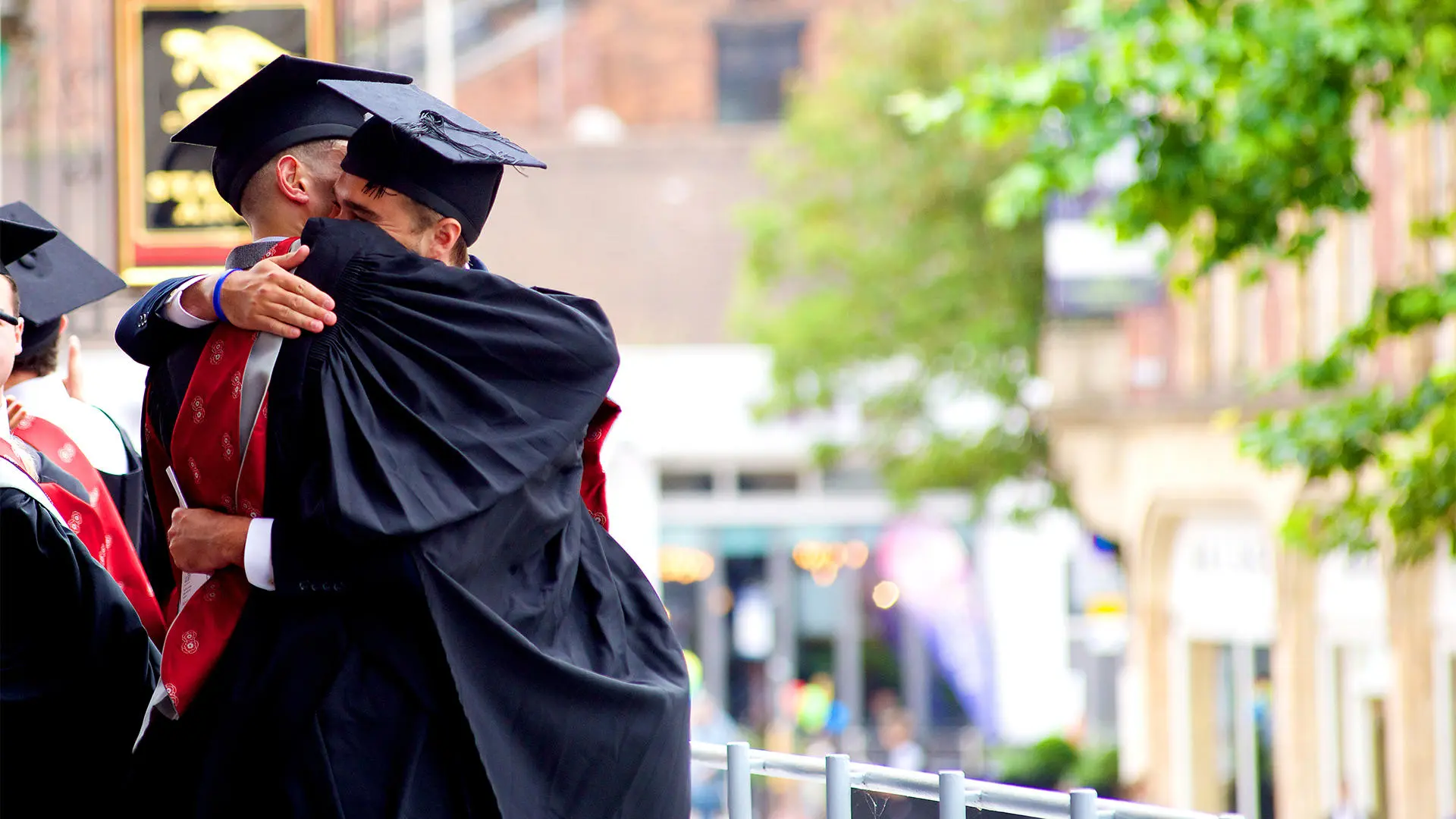 Two graduates hugging in gowns