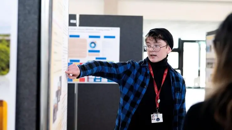 A student talking about their work at the Undergraduate Research Internship Programme competition poster display. 