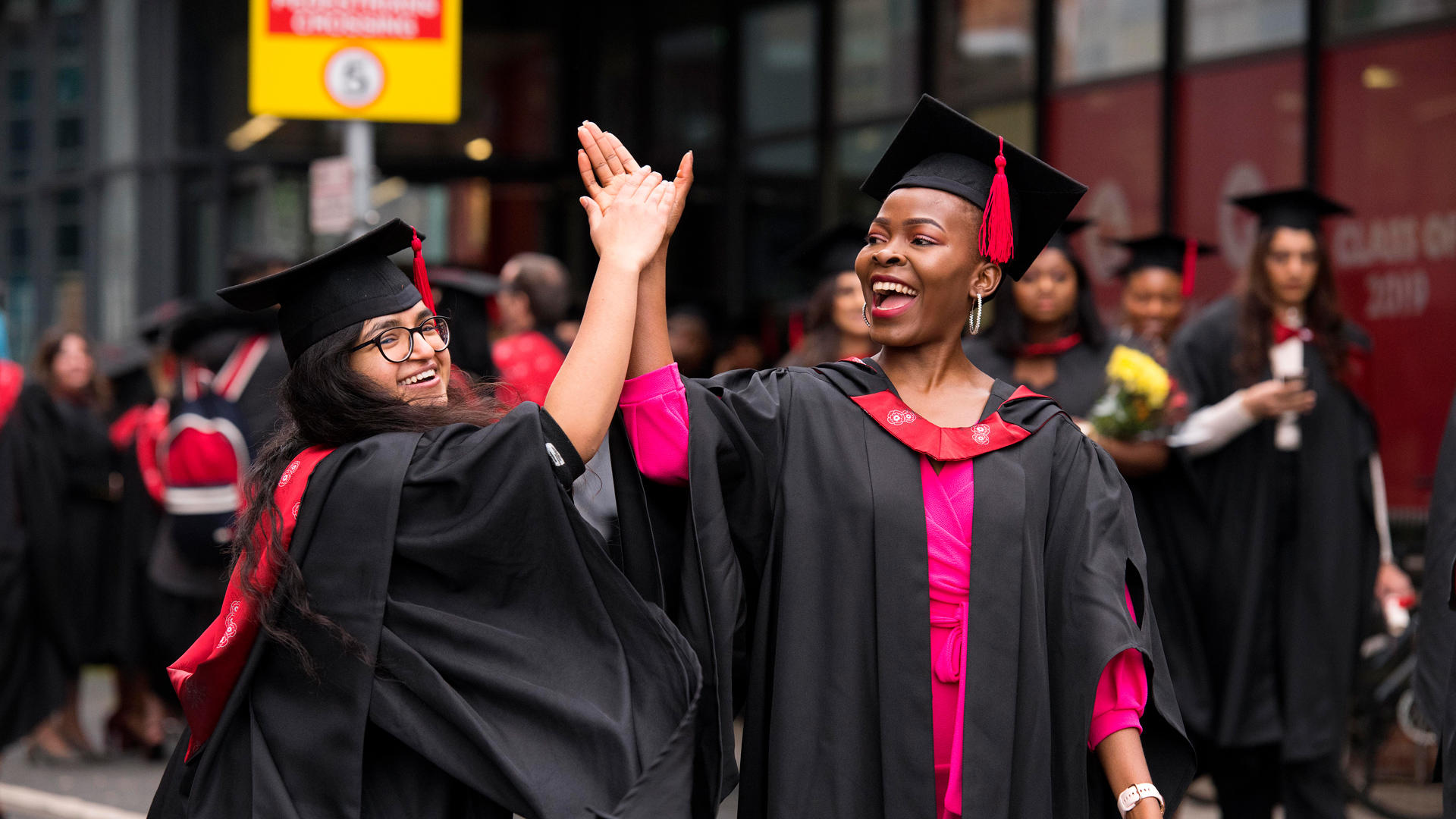 Smiling graduates giving a high-five