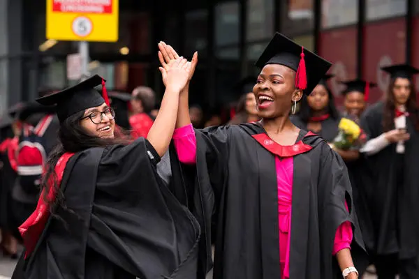 Smiling graduates giving a high-five