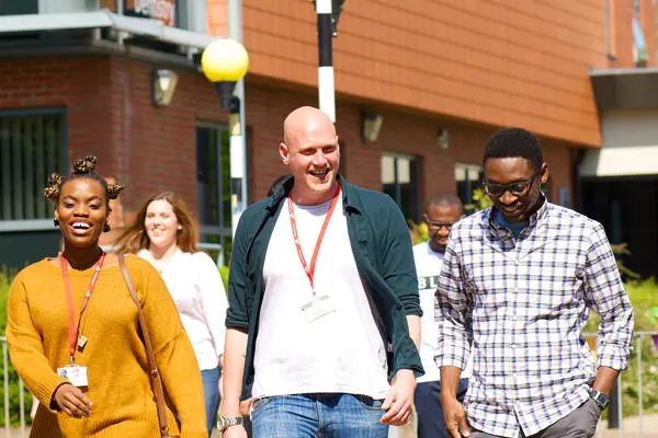 Group of smiling students walking through a sunny campus