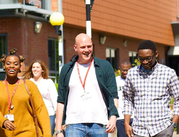 Group of smiling students walking through a sunny campus