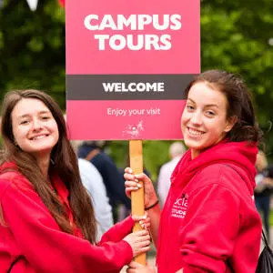 Student volunteers holding a 'campus tours' sign