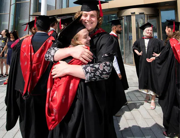 Two graduates embracing outside the new student centre