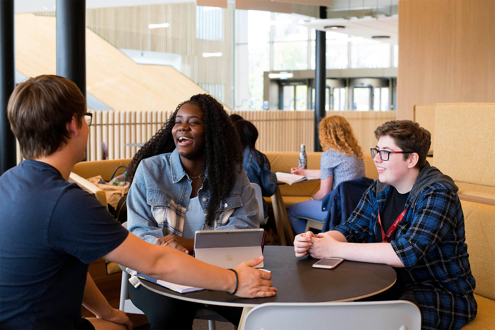 Students laughing sitting around a table in student centre