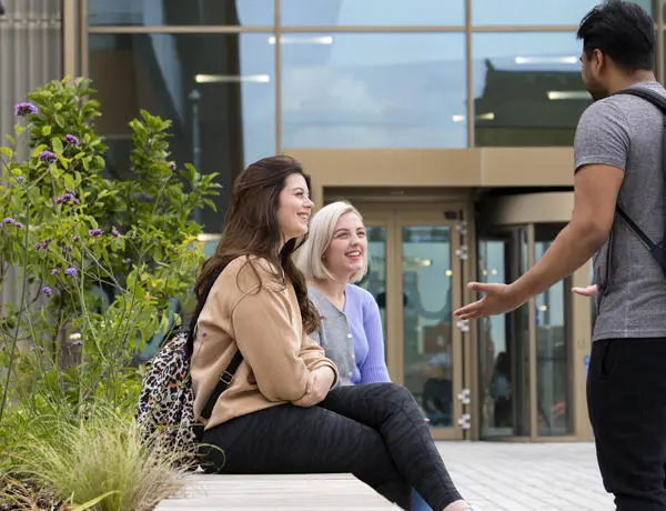 Students sat on a bench outside the student centre at our Preston campus