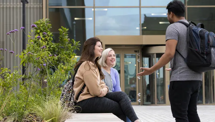 Students sat on a bench outside the student centre at our Preston campus