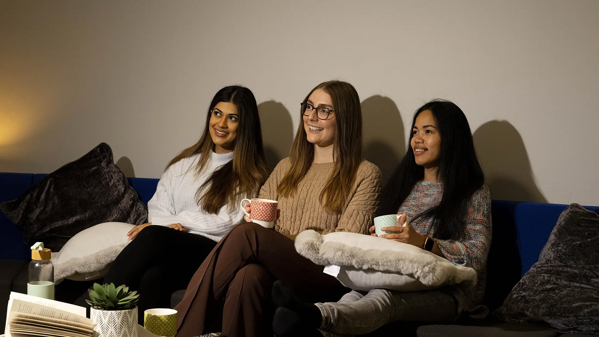 students sat on the sofa in the evening with cups of tea