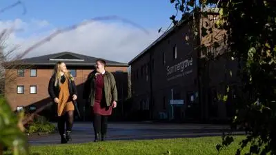 A pair of students walk together outside of Summergrove Halls