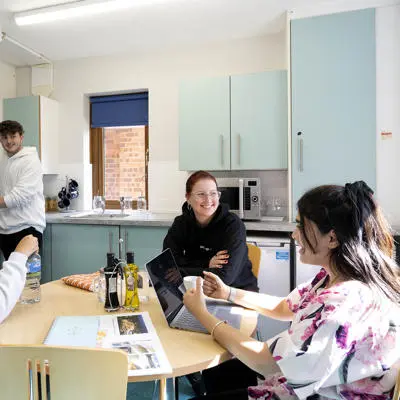 Group of students sat in shared kitchen of flat around the table