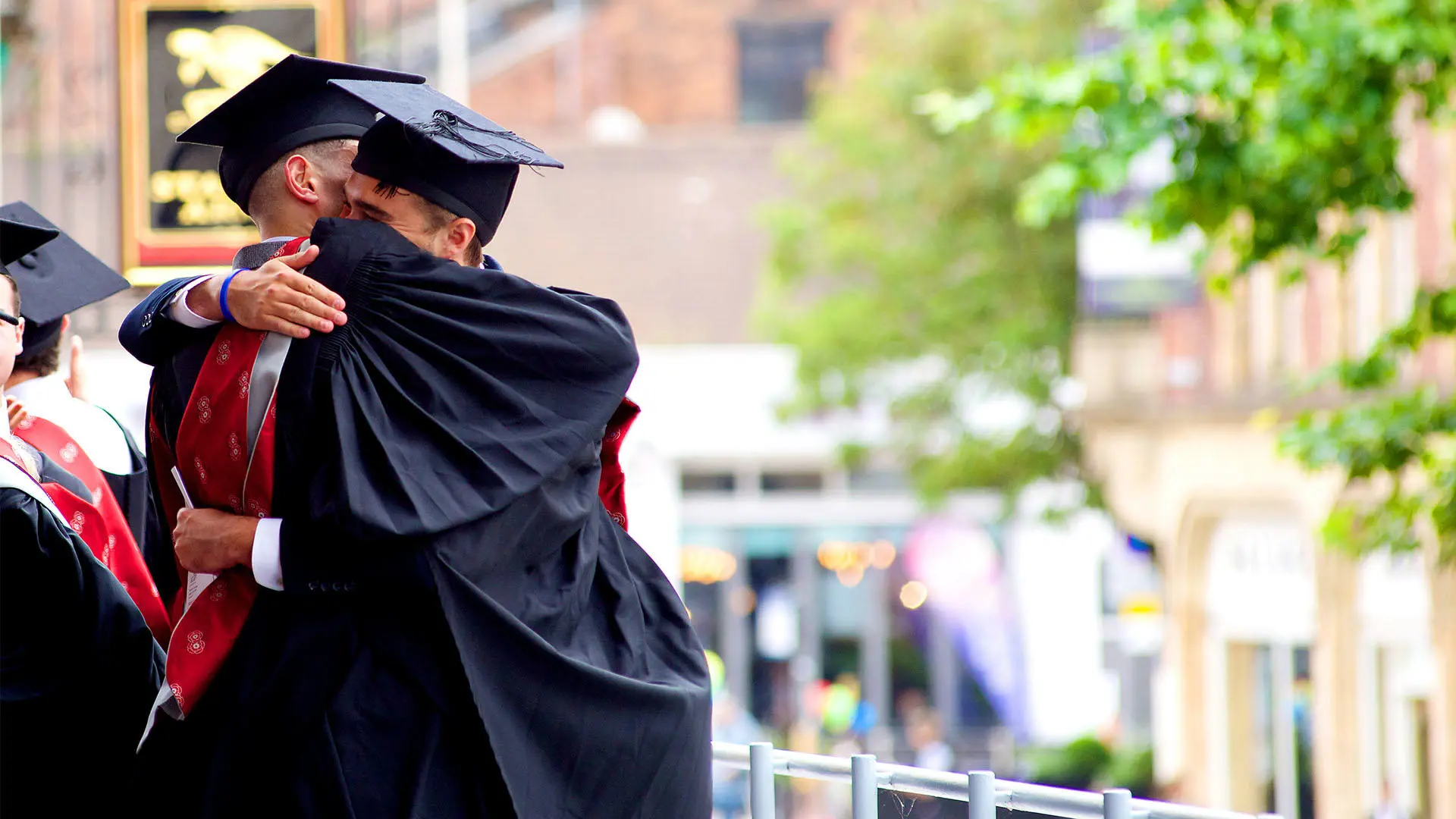 Graduates hugging in graduation gown and hat