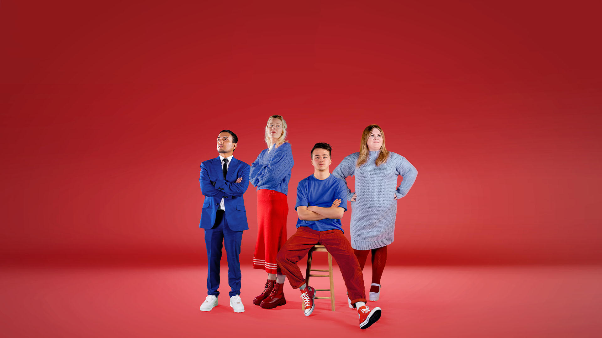 Four business students stood together in front of red backdrop