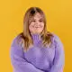 International Business student Jess Holden wearing purple jumper in front of a yellow background