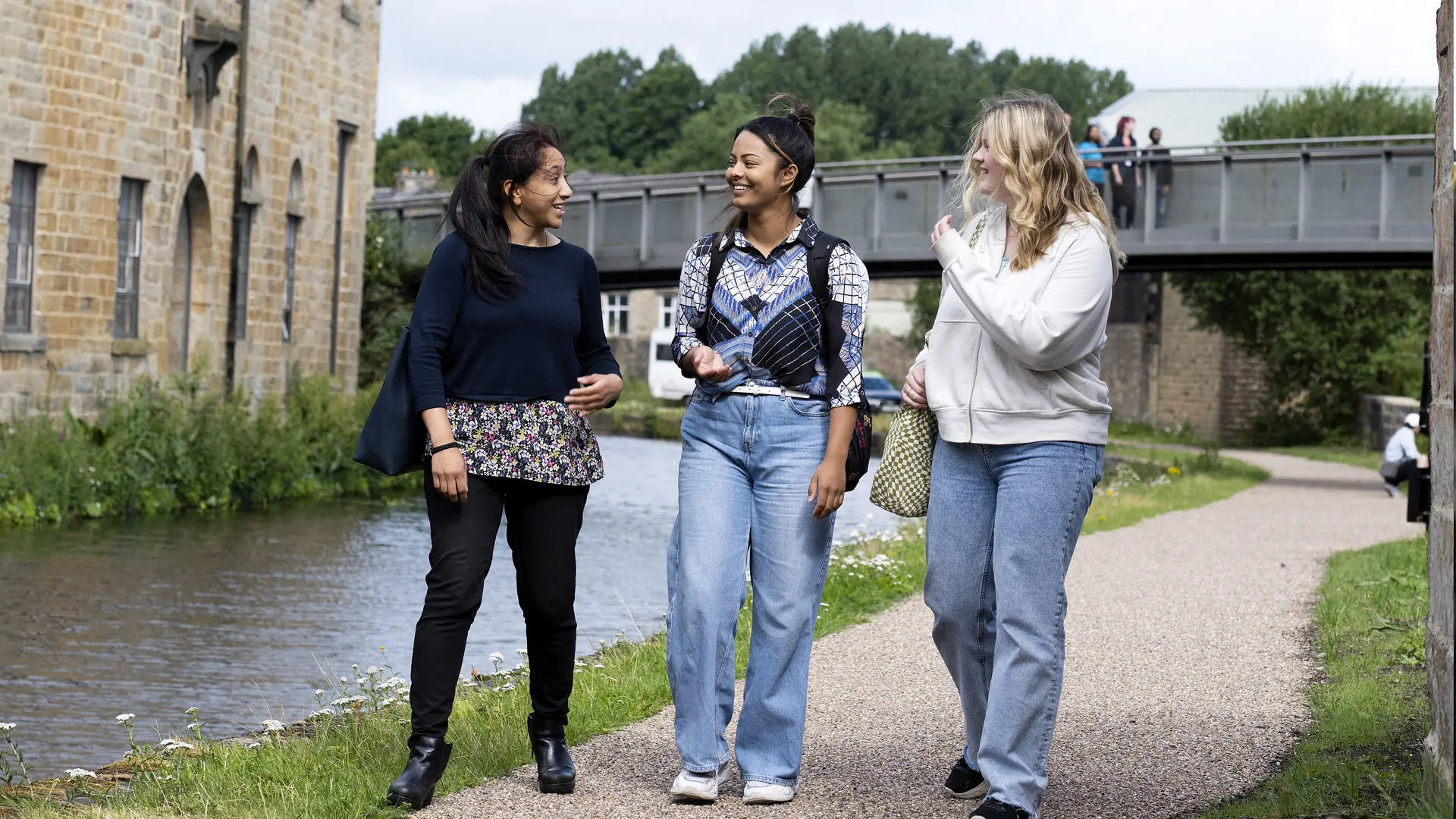 three students walking next to the canal in burnley chatting