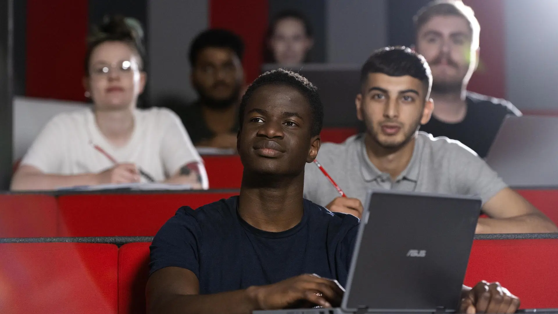 Students sit and take note in a modern lecture theatre.