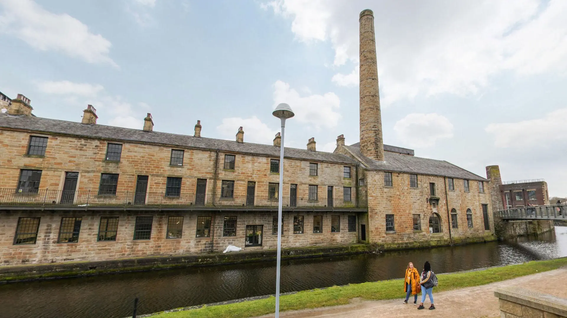 Students walking in front of the canal at Sandygate Mill, Burnley Campus