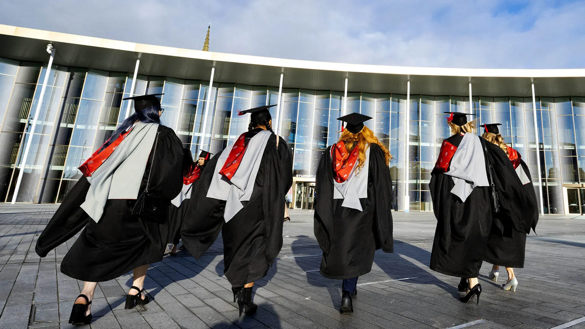 group of students in graduation gowns walking towards the student centre