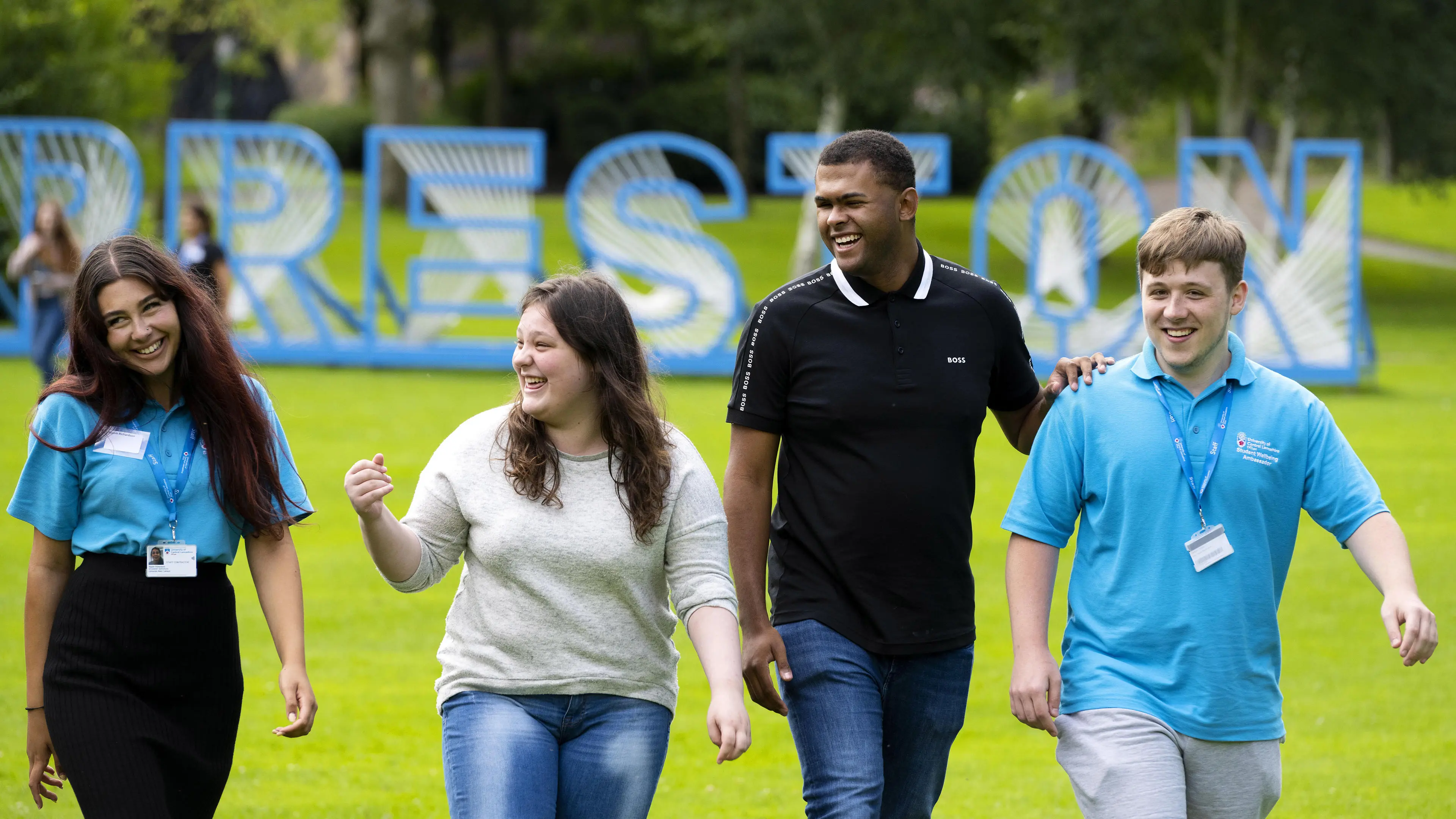 A group of students and wellbeing ambassadors walk through a park in Preston.
