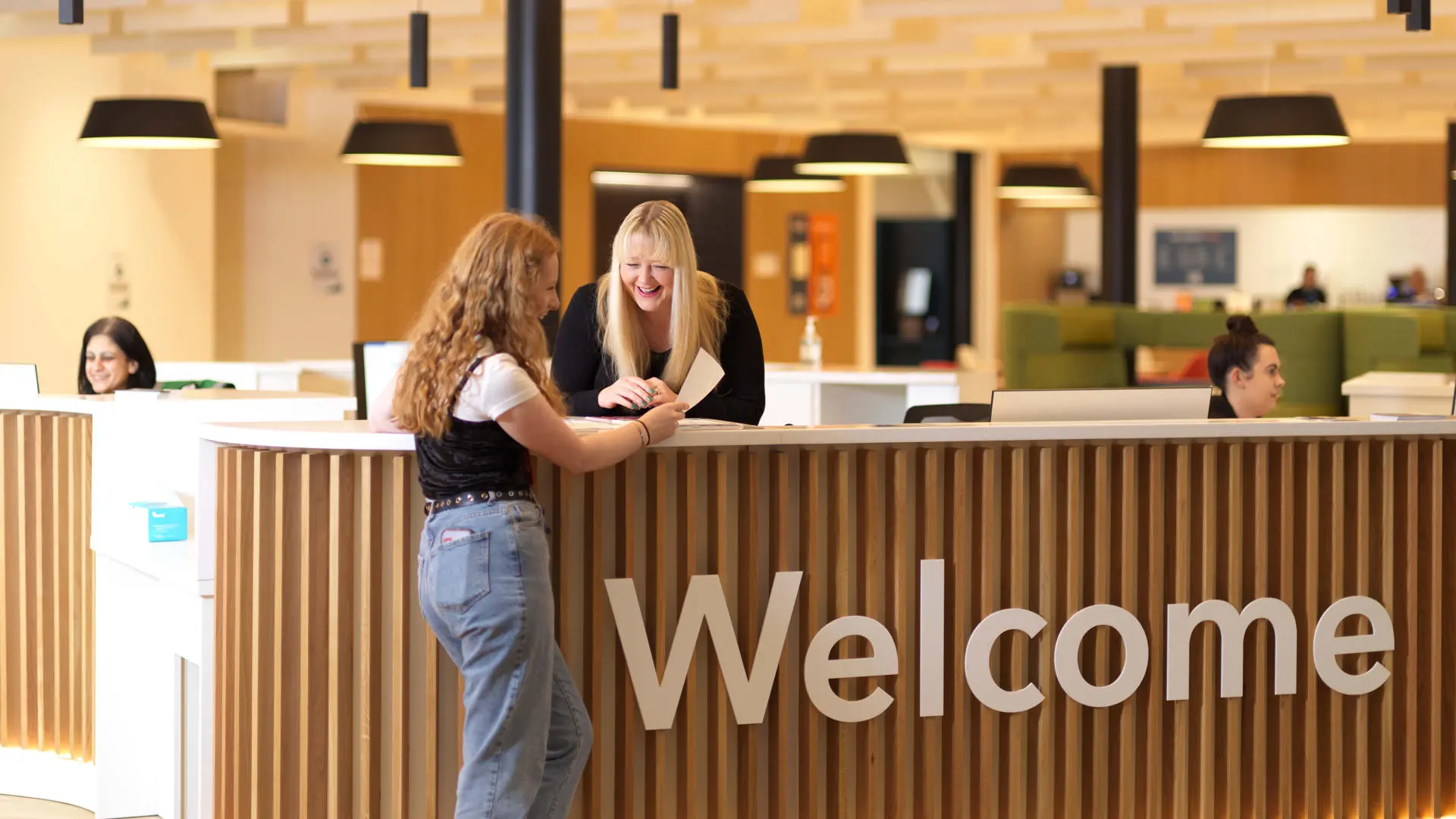 female student asking a question at the welcome desk