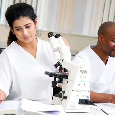 mbbs medicine students working together and looking through microscopes