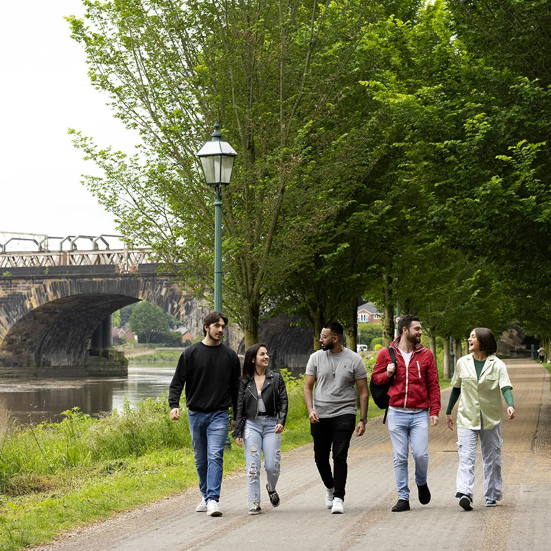 Group of students walking alongside the river ribble in avenham park
