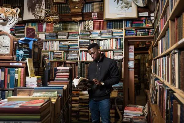 student holding and looking at a book in a old fashioned book shop