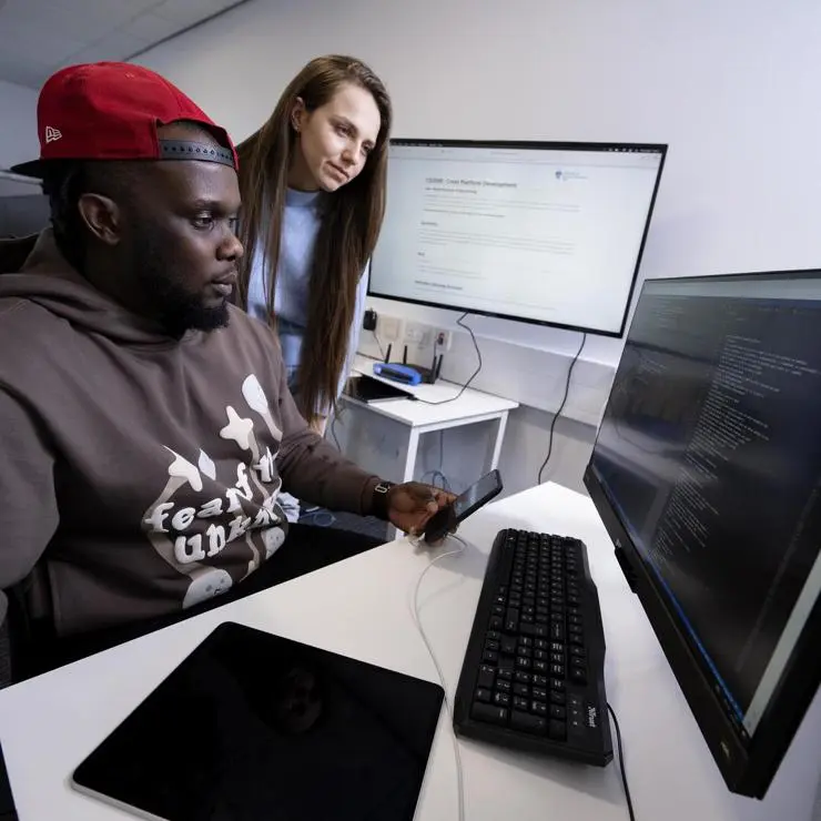 Two students pair programming with specialised hardware for software development.