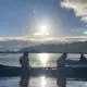 Students canoeing on a lake with the sun in the background
