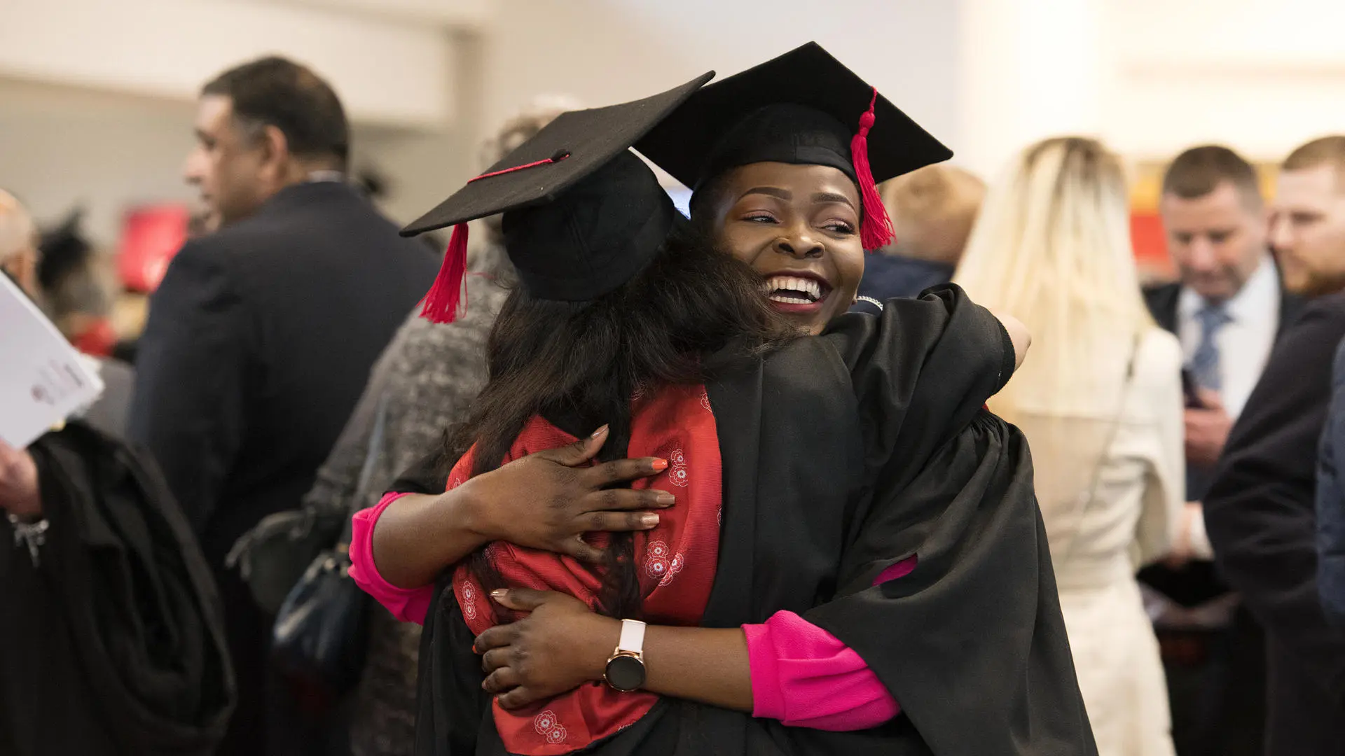graduating students hugging each other in their graduation robes
