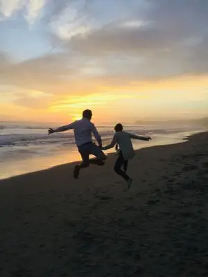 Two people jumping on beach.