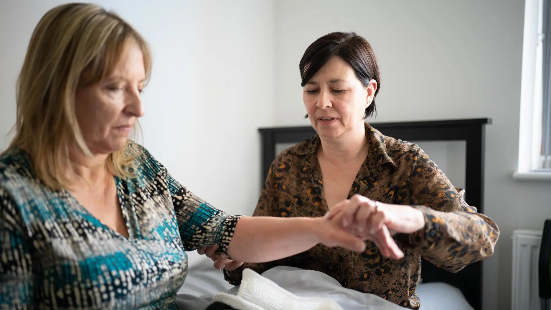 A health professional helps a stroke recovery patient with their arm