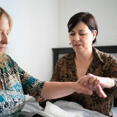 A health professional helps a stroke recovery patient with their arm