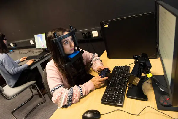 Psychology researcher wearing test equipment while working at a computer