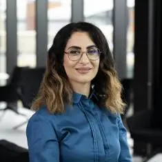 Leila Khajenoori in a blue blouse and glasses smiling