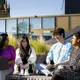 four international students sat on the roof terrace of the student centre on a bench on a sunny day