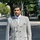 Hamad in a grey suit outside