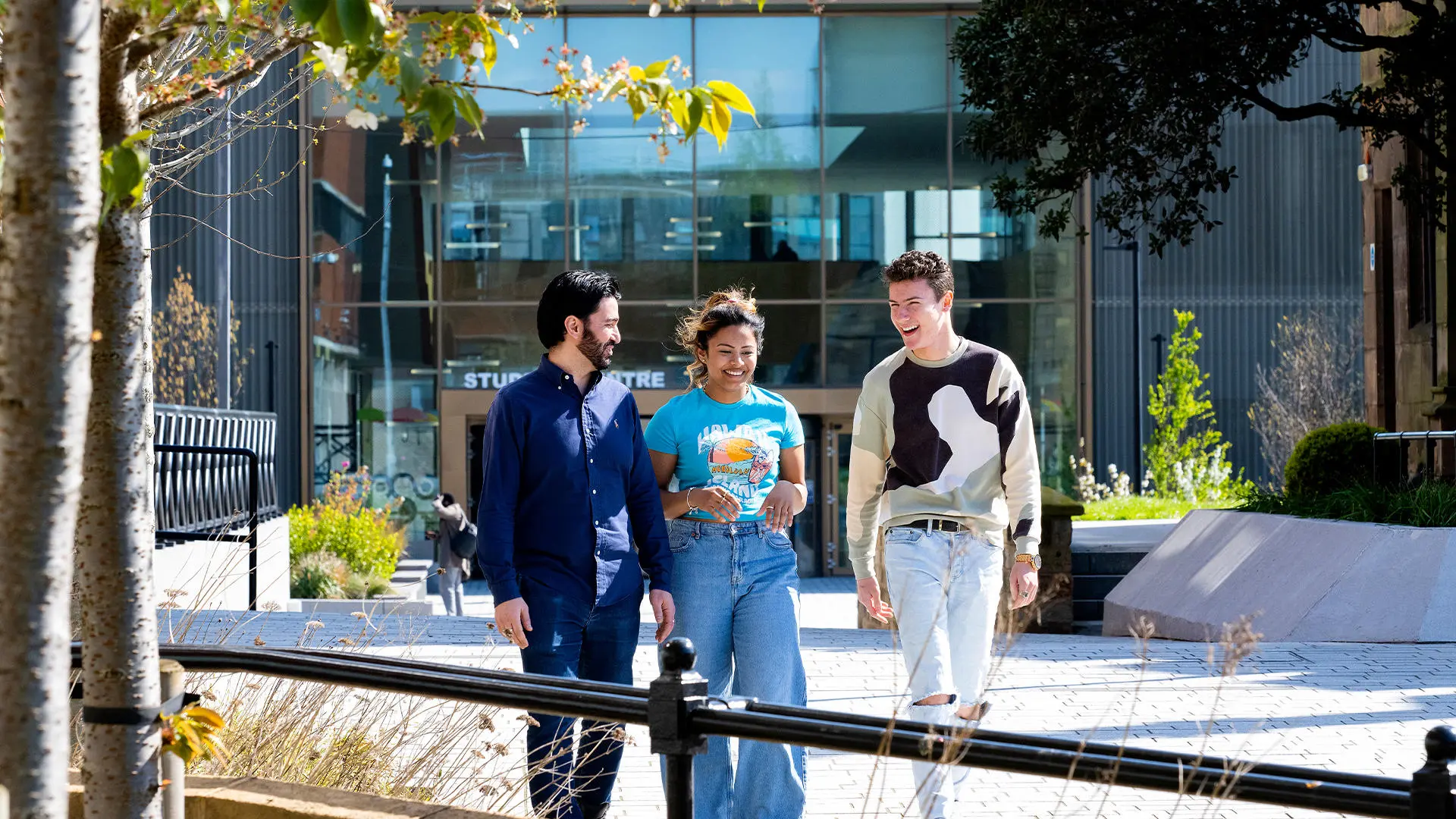 Three students walking on Preston campus in the sunshine