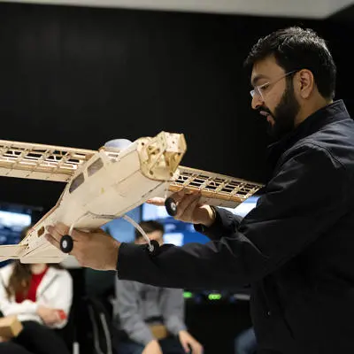 A lecturer demonstrates aerospace engineering with a model aeroplane