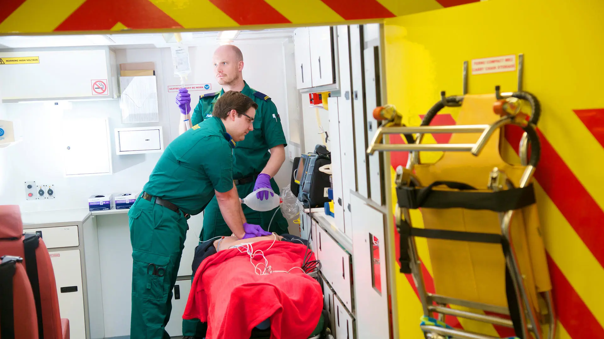 two students working on a dummy in the back of an ambulance