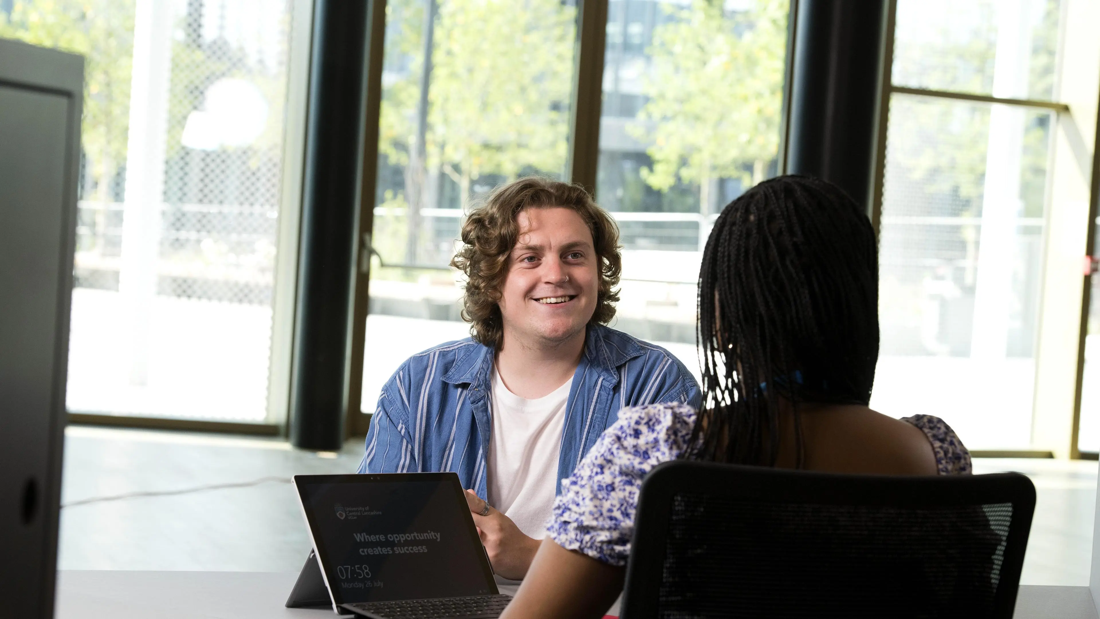 Student facing a member of staff in the Student Centre