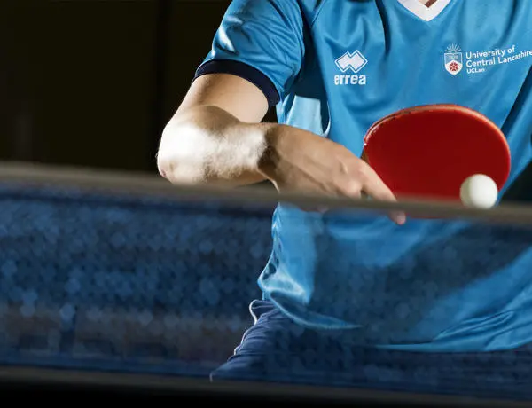 person hitting a table tennis ball against a net