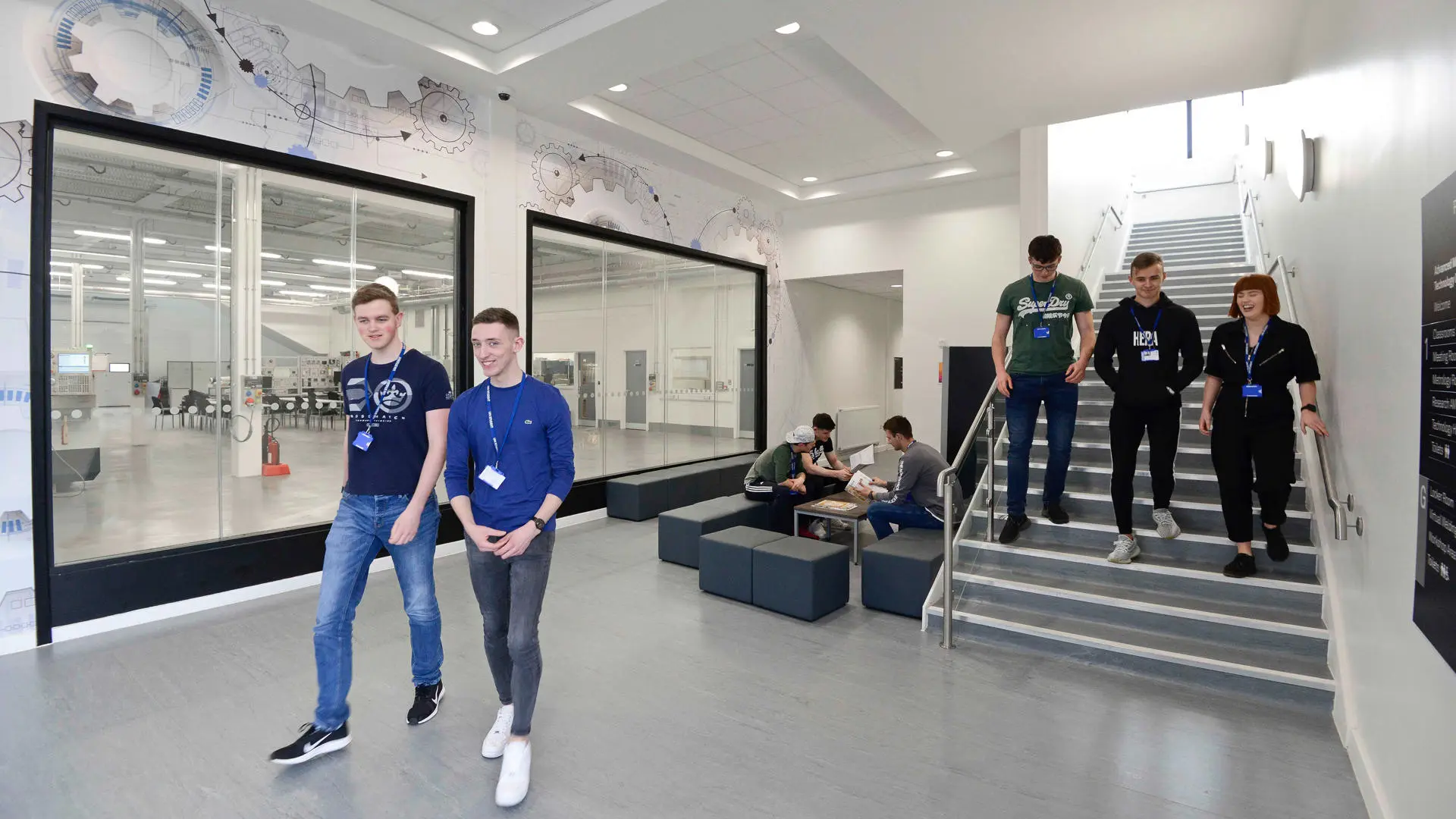 Students walking down stairs inside modern looking campus building