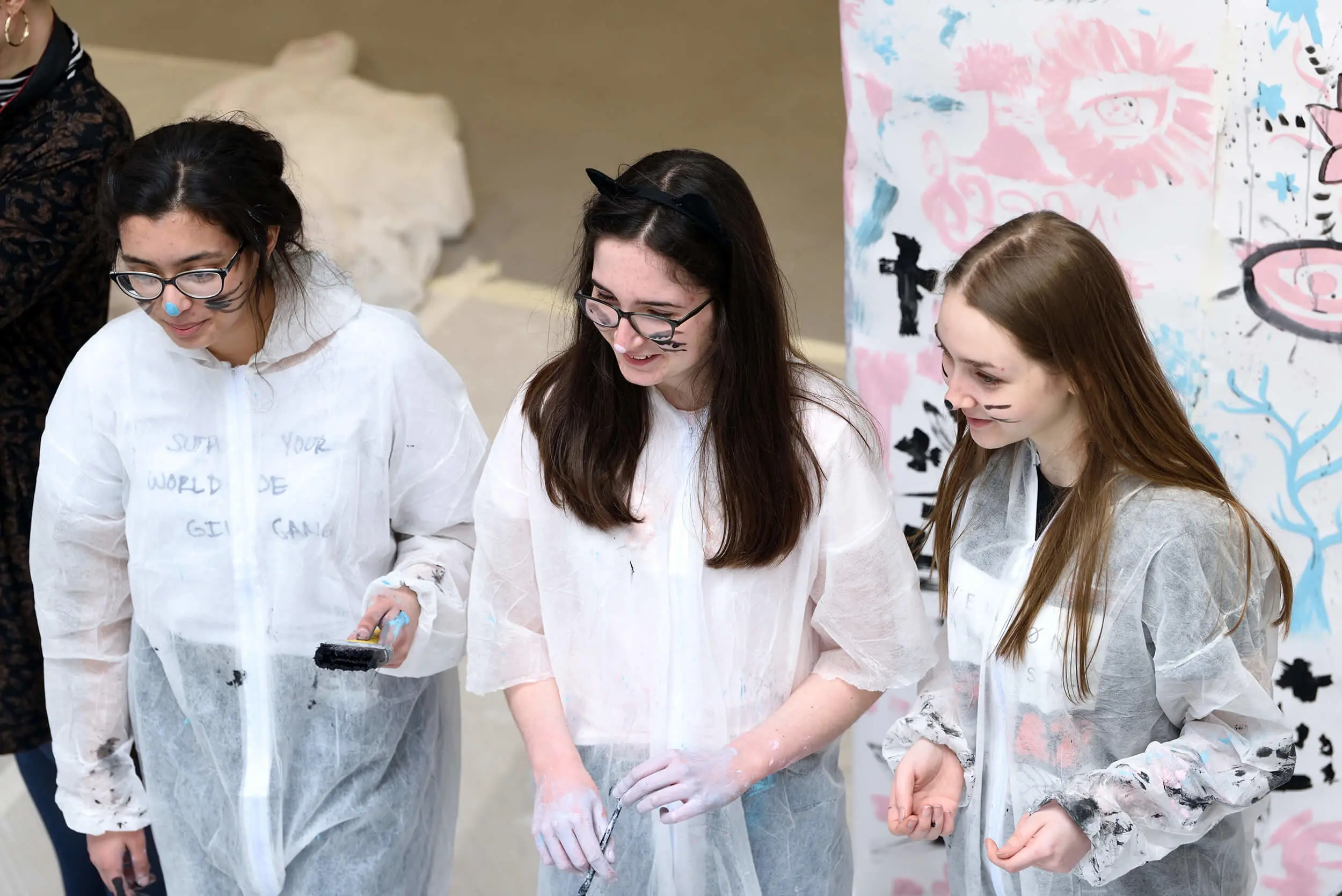 Three young people in protective overalls taking part in art workshop