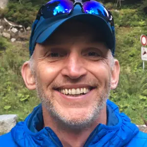 Jeremy outdoors in a blue jacket and blue cap smiling