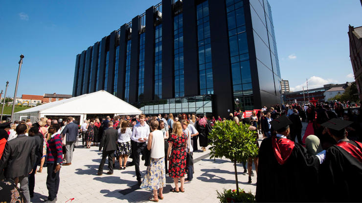 Guests gathering in the sun outside a graduation ceremony