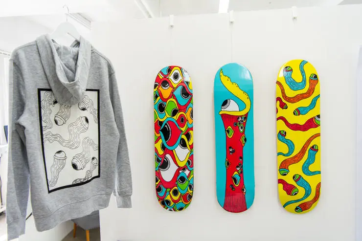 A grey hoodie and three vibrant skateboards hanging on a wall