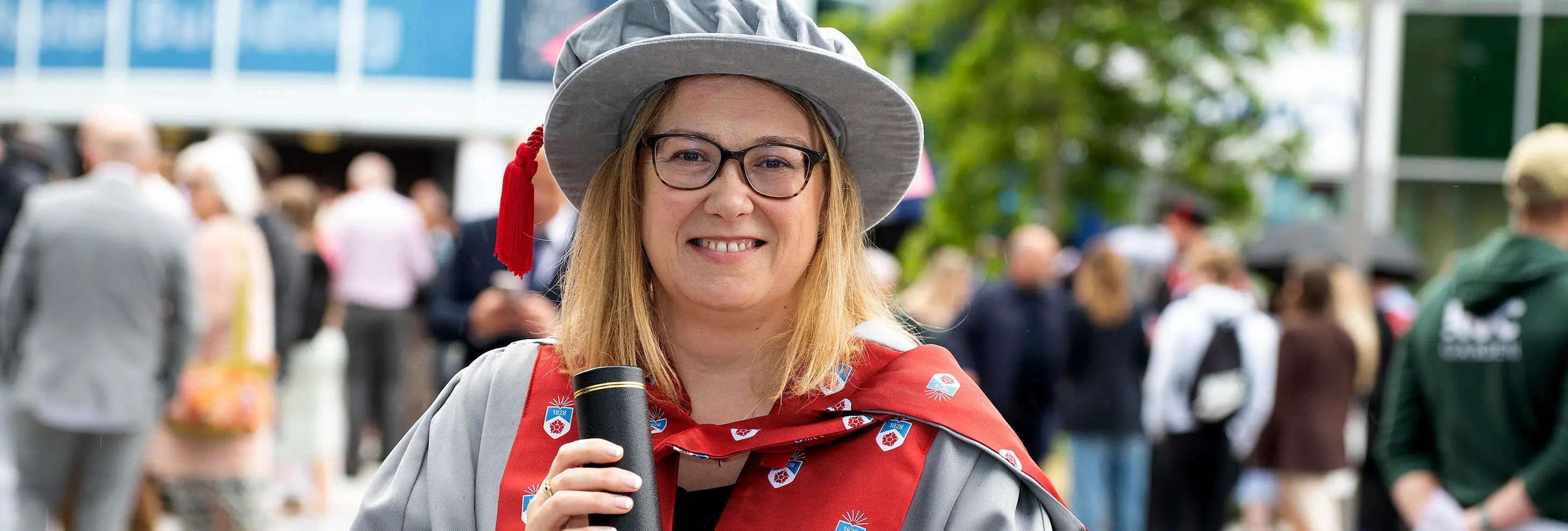 Alison McLoughlin wearing academic robes while holding a scroll