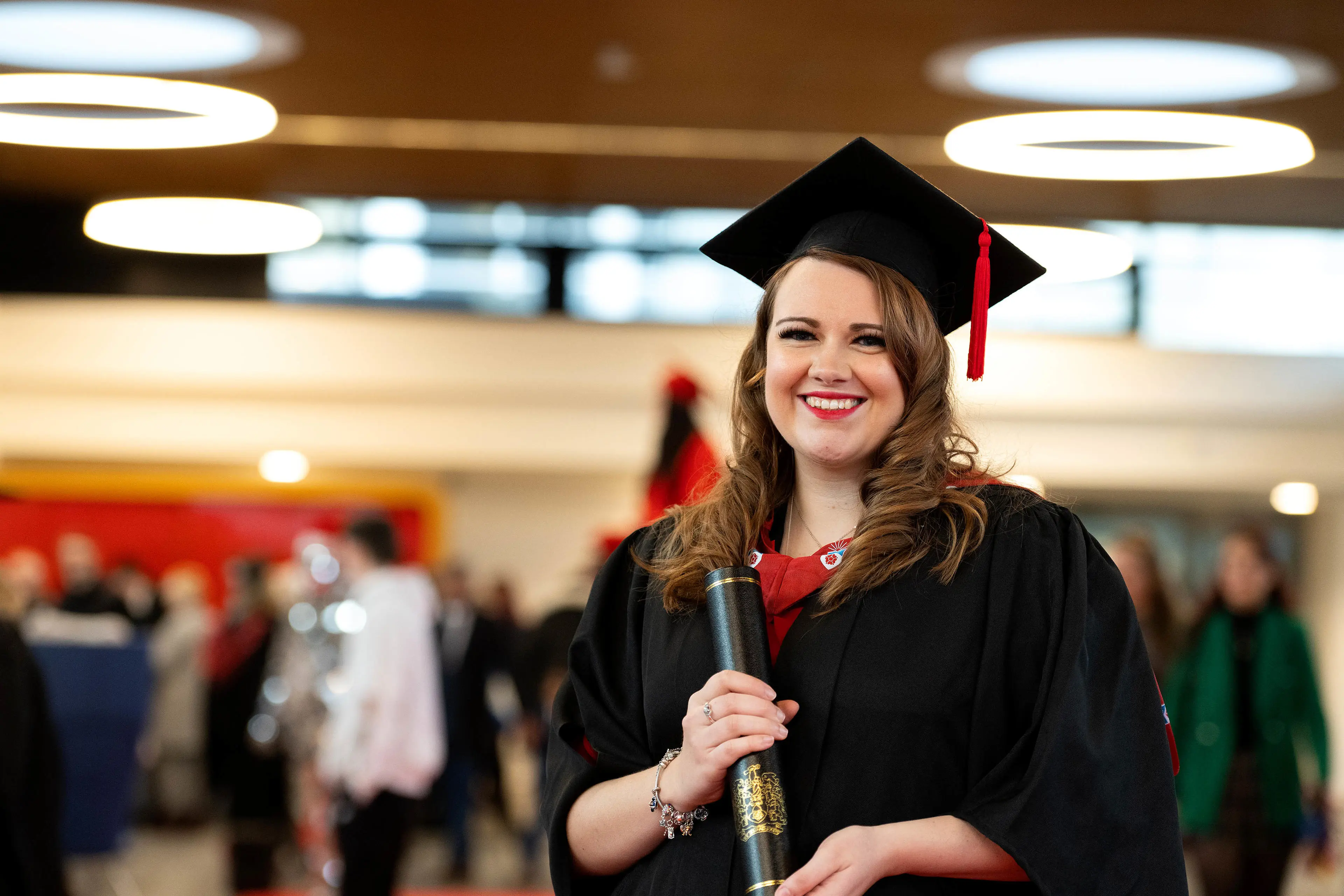 Angie Gudgeon wearing a cap and gown holding a scroll